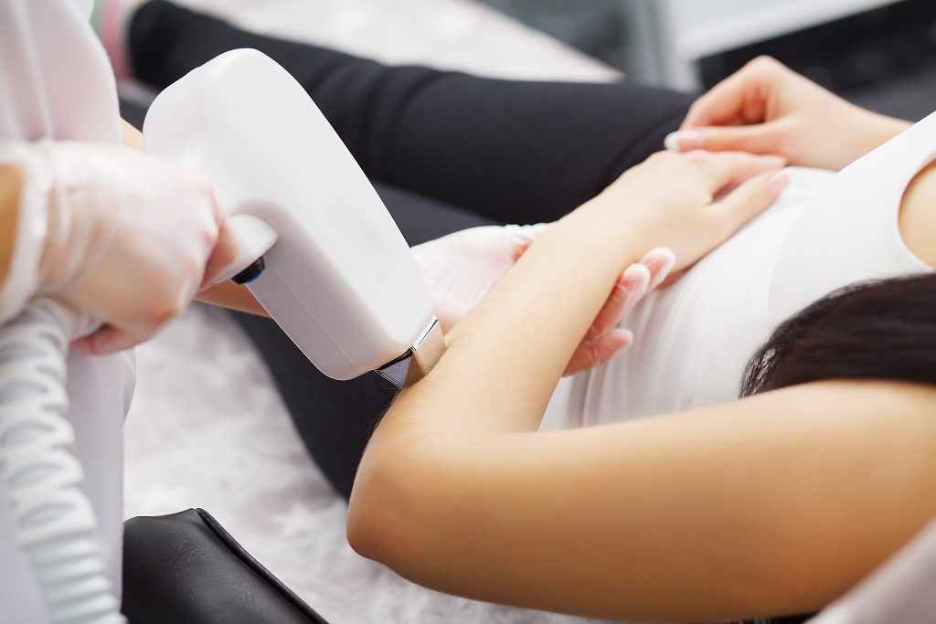 body care. underarm laser hair removal. beautician removing hair of young woman's armpit. laser epilation treatment in cosmetic beauty clinic. hairless smooth and soft skin. health and beauty concept.