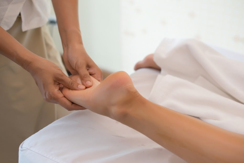 close up of massage therapist massaging female leg at spa salon.